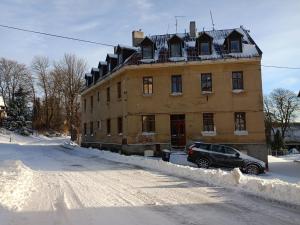 une voiture garée devant un bâtiment dans la neige dans l'établissement Apartmán Matylda, à Abertamy