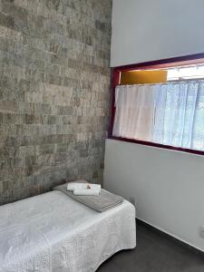 um quarto com uma cama e uma parede de tijolos em Pousada Canto Verde em Serra do Cipó