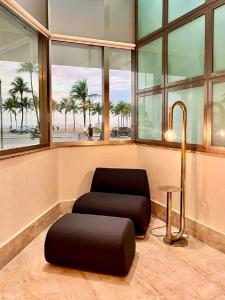 une chambre avec une chaise, une table et des fenêtres dans l'établissement Hotel Astoria Palace, à Rio de Janeiro