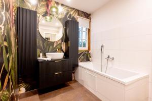 La salle de bains est pourvue d'un lavabo, d'une baignoire et d'un miroir. dans l'établissement LIT LIVING Weinheim Altstadt - Boutique Apartments, à Weinheim