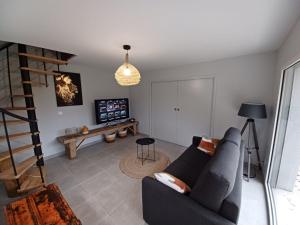 a living room with a couch and a tv at Chez Emoun et Lina in Caussade +2 photos