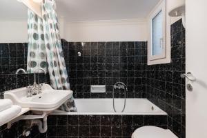 a black tiled bathroom with a sink and a tub at Lovely Apartment in Exarcheia in Athens