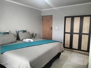 a bedroom with a large bed with a blue blanket at AKANI Guesthouse Cosmo city in Roodepoort
