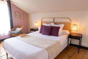 a bedroom with a large white bed with purple pillows at La maison d'Yport in Yport