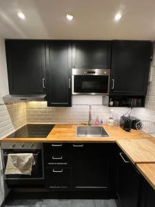 a kitchen with black cabinets and a sink and a microwave at Vanves : 2 pièces lumineux aux portes de Paris in Vanves
