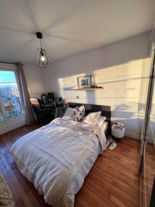 a bedroom with a large white bed with a window at Vanves : 2 pièces lumineux aux portes de Paris in Vanves