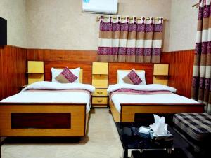 a bedroom with two beds and a table with a basket at Jinnah Airport Hotel in Karachi