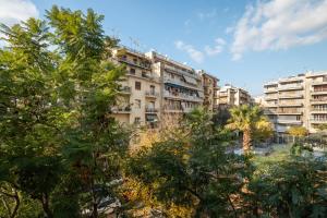 um prédio de apartamentos com árvores em frente em Lovely Apartment in Exarcheia em Atenas