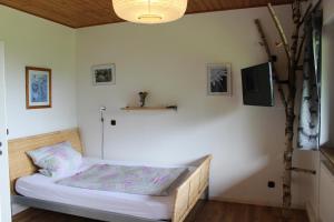 Bett in einem Zimmer mit einer weißen Wand in der Unterkunft Ferienhaus Waldidyll in Langfurth 