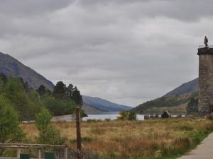 a lighthouse in a field next to a body of water at 3 Bed in Fort William CABIN in Glenfinnan