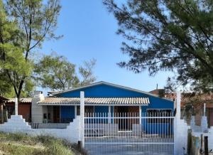 ein blaues Haus mit einem weißen Zaun in der Unterkunft Casa Pé na Arreia in Arroio do Silva