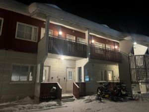 a house with a motorcycle parked in the snow at night at Cozy studio with sauna in the middle of Levi in Kittilä