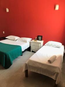 twee bedden in een kamer met een rode muur bij Babeu suites independentes in Rio de Janeiro