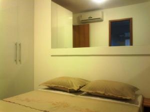 1 cama con 2 almohadas en una habitación con espejo en Apartamento Dois Quartos, en Recife