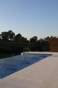 una piscina de agua azul y una terraza de madera en Zambujal Suites, en Sesimbra