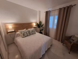 Luxury Apartment in Playas del Duque , Puerto Banus by Holidays & Home في مربلة: غرفة نوم بسرير ونافذة وكرسي