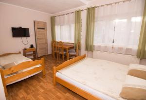 a bedroom with two beds and a table with a television at Willa Nova - Centrum in Szklarska Poręba
