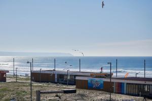 a beach with birds flying over the ocean at Stunning Beach Sunset View, By TimeCooler in Costa da Caparica