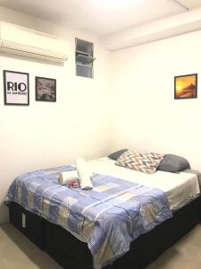 een slaapkamer met een bed met een blauwe deken erop bij Babeu suites independentes in Rio de Janeiro