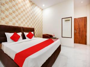 1 dormitorio con 1 cama grande con almohadas rojas en OYO Flagship Golden A en Ludhiana