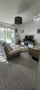 sala de estar con sofá y cocina en Maison Cosy, en Franconville