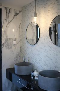 a bathroom with two sinks and two mirrors at Zambujal Suites in Sesimbra