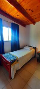 a bedroom with a bed with blue curtains and a window at Casa V.Giardino pileta y cochera in Villa Giardino