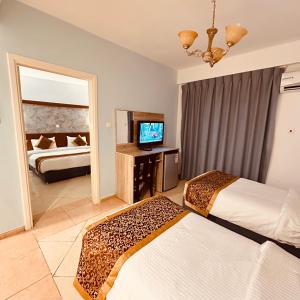 a hotel room with two beds and a television at Aquavista Hotel & Suites in Aqaba