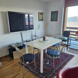 sala de estar con mesa, sillas y TV en Appartement meublé à louer à Nax, en Nax