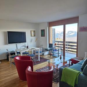 a living room with a table and chairs and a television at Appartement meublé à louer à Nax in Nax