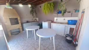 a small kitchen with two white tables and a stove at Conforto e Tranquilidade in Poços de Caldas