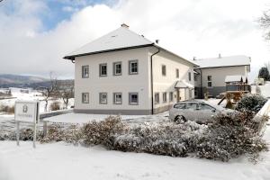 ein weißes Haus mit einem Auto im Schnee in der Unterkunft HOCHFICHTBLICK Apartments in Ulrichsberg