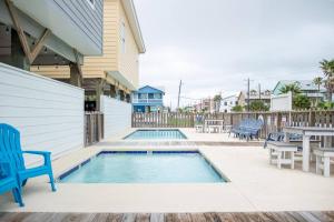 a swimming pool with two blue chairs and a table at Beach Bungalow - 2 Suns in Port Aransas