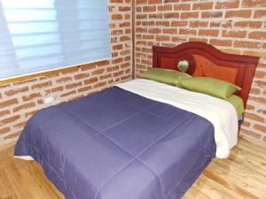 Ce lit se trouve dans une chambre dotée d'un mur en briques. dans l'établissement Villa Don Alonso: Casa de Campo, à Penipe