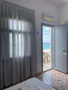 a bedroom with a sliding glass door with a view of the ocean at Chrisopetro Rooms in Marathokampos