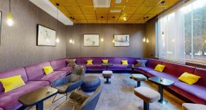 a waiting room with purple couches and yellow pillows at PLAZA INN Regensburg in Regensburg +37 photos