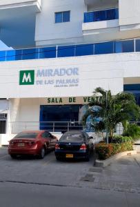 apartaestudio independiente en Manga, Cartagena في كارتاهينا دي اندياس: سيارتين متوقفتين في موقف للسيارات امام مبنى