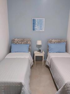 2 letti in una stanza con un tavolo tra loro di B&B Carpe Diem a Gravina di Catania