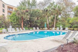 a large swimming pool with chairs and palm trees at Great beach GETAWAY. Walking distance of the Beach in Hilton Head Island