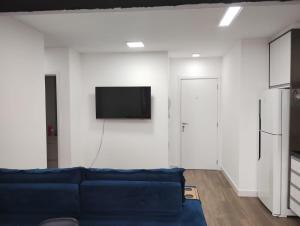 ein Wohnzimmer mit einem blauen Sofa und einem TV an der Wand in der Unterkunft Piscine Resort Brás in São Paulo