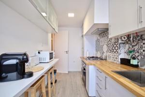 una cocina con armarios blancos y encimeras de madera en Akicity Amoreiras Jade, en Lisboa