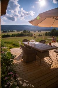 a wooden deck with a table with chairs and an umbrella at Przystanek Lasówka in Lasowka