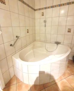 a white tub in a white tiled bathroom at Cozy Appartement Belvaux in Belvaux