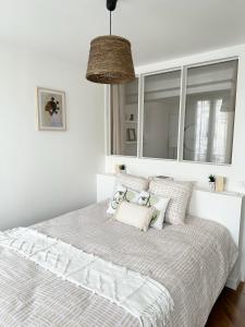 a bedroom with a bed with pillows and a mirror at Appartement central niché en centre-ville in Saint-Germain-en-Laye