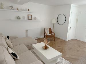 a white living room with a couch and a table at Appartement central niché en centre-ville in Saint-Germain-en-Laye