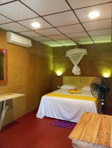 a room with a bed with a fan and a table at Nature lovers safari House in Udawalawe