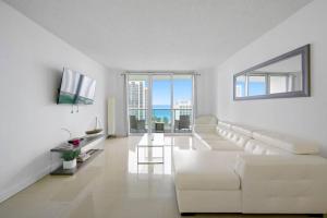 a white living room with a white couch and large windows at Ocean View 15th floor Apartment Sunny Isles in Sunny Isles Beach