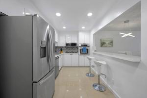 a kitchen with white cabinets and a refrigerator at Ocean View 15th floor Apartment Sunny Isles in Sunny Isles Beach