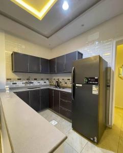 a kitchen with black cabinets and a stainless steel refrigerator at شاليهات الود in Abha