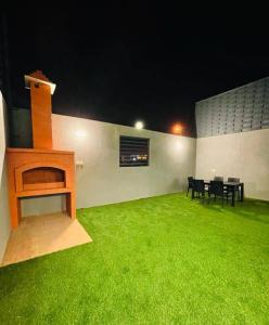 Zimmer mit einem grünen Garten mit einem Tisch und Stühlen in der Unterkunft شاليهات الود in Abha